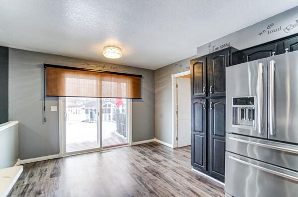 kitchen with stainless steel fridge, a textured ceiling, and light wood-type flooring