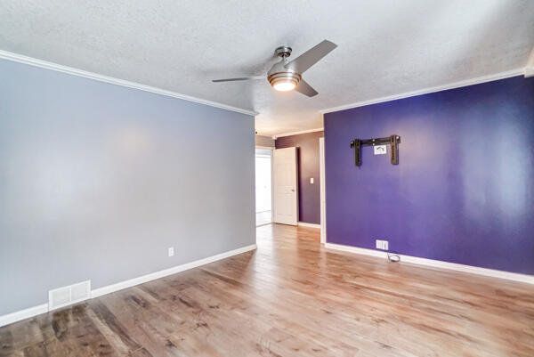 spare room with crown molding, a textured ceiling, ceiling fan, and light hardwood / wood-style floors