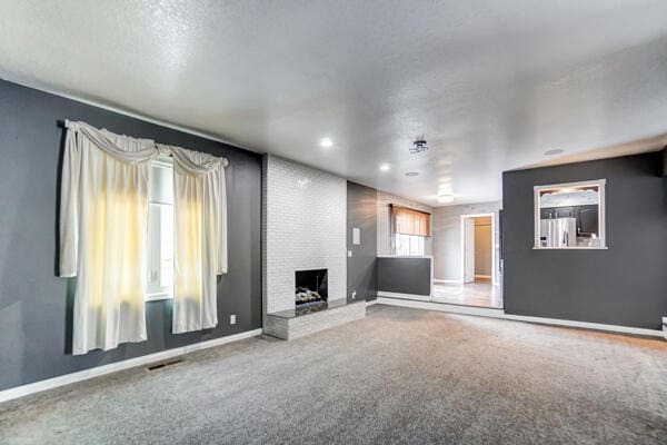 unfurnished living room featuring carpet flooring and a fireplace