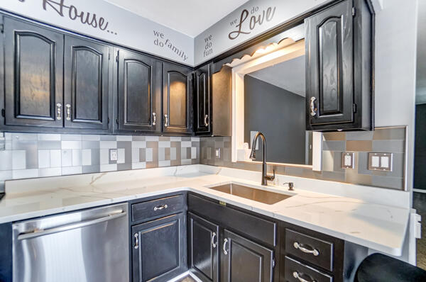 kitchen with light stone counters, dishwasher, sink, and backsplash