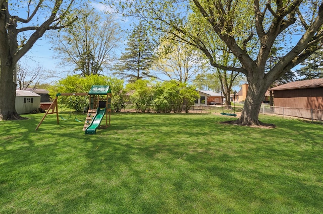 view of yard with fence, an outbuilding, a shed, and a playground