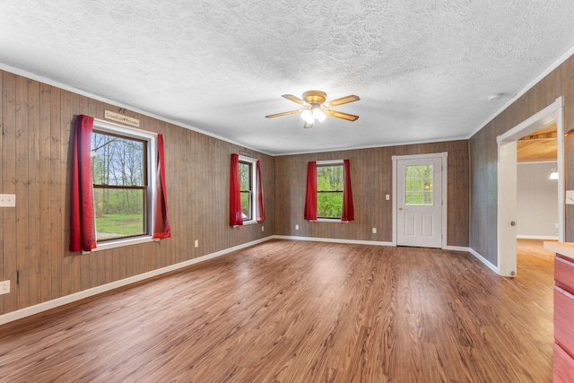 interior space with crown molding, a ceiling fan, wood finished floors, and a healthy amount of sunlight
