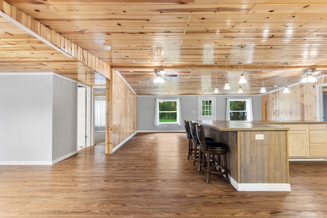 kitchen with dark wood-style flooring, a ceiling fan, and wood walls