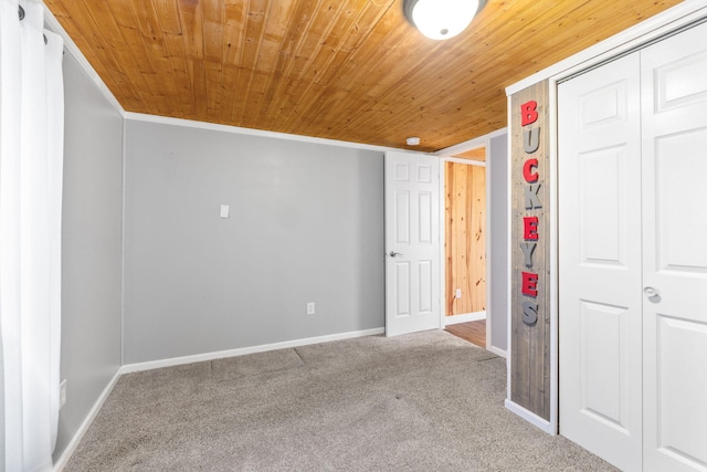 unfurnished bedroom featuring carpet flooring, baseboards, wooden ceiling, and a closet