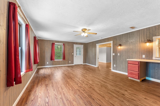 unfurnished living room featuring a textured ceiling, ceiling fan, wood finished floors, and visible vents