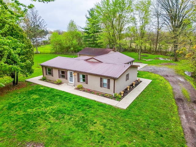 back of house featuring a lawn, driveway, and metal roof