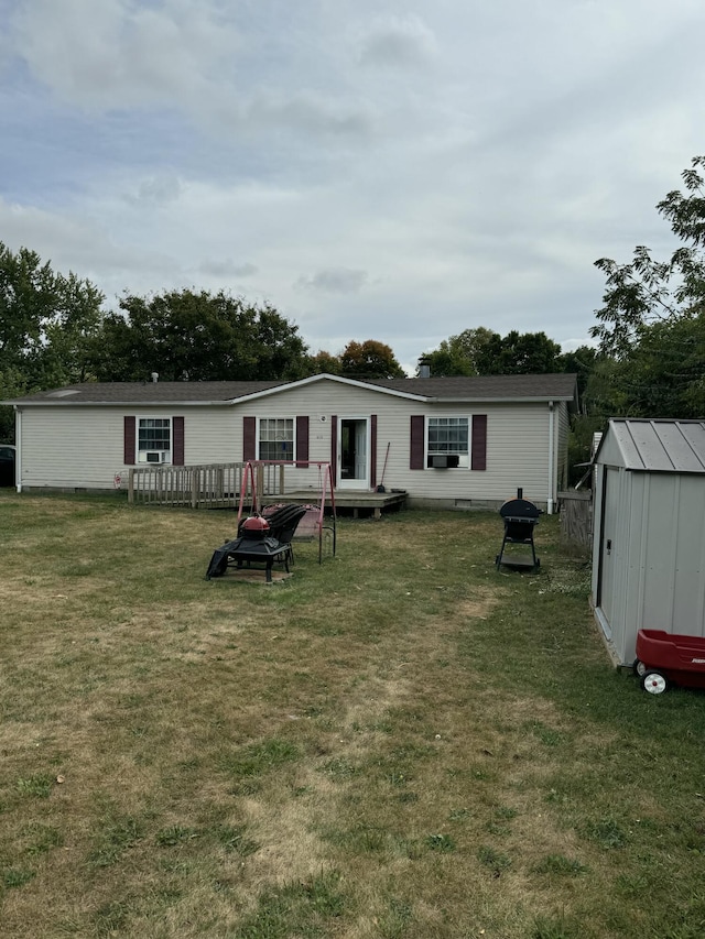 rear view of house featuring a lawn and a storage unit