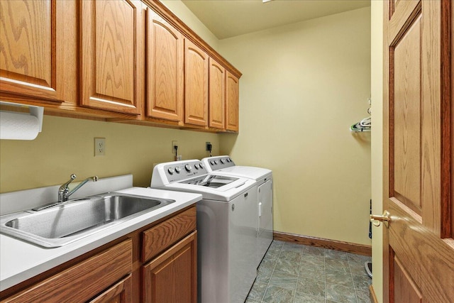 laundry room featuring baseboards, cabinet space, independent washer and dryer, and a sink