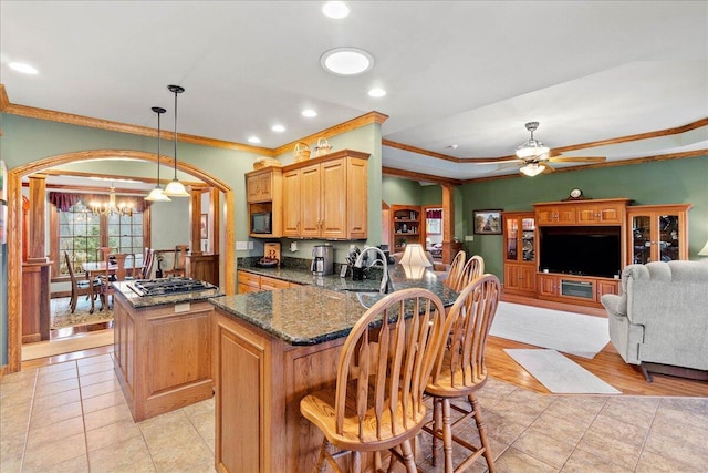 kitchen featuring dark stone counters, a center island, black gas cooktop, a sink, and ceiling fan with notable chandelier