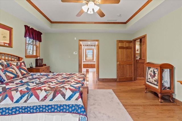 bedroom featuring ornamental molding, a raised ceiling, visible vents, and wood finished floors