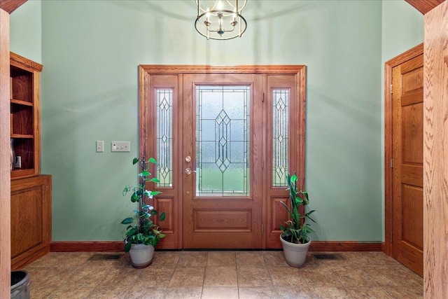 foyer with a notable chandelier, visible vents, and baseboards