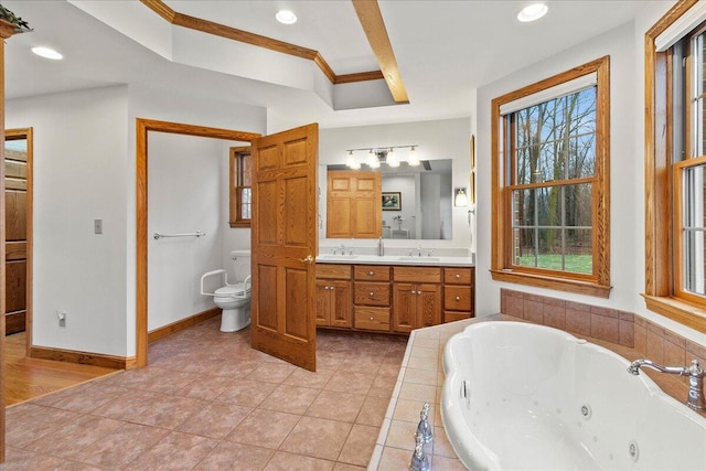 bathroom with toilet, vanity, tile patterned flooring, baseboards, and a tub with jets