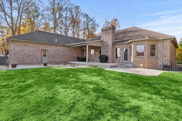 rear view of property with a patio area, a yard, and brick siding