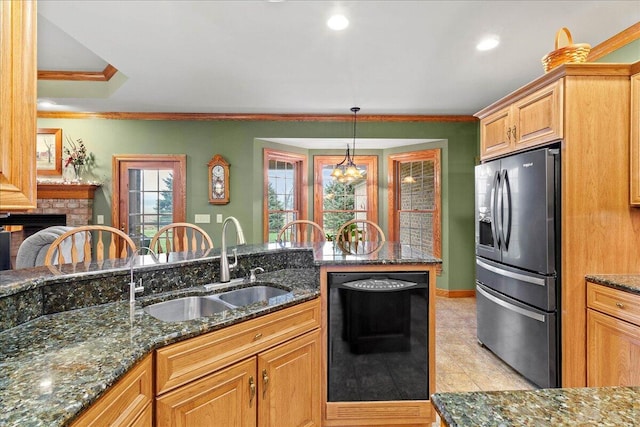 kitchen featuring a sink, ornamental molding, stainless steel refrigerator with ice dispenser, a brick fireplace, and dishwasher