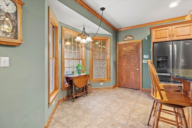 dining area featuring an inviting chandelier, baseboards, and ornamental molding