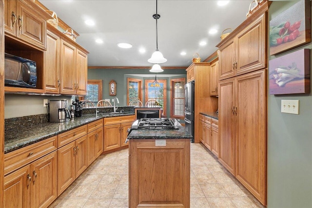 kitchen featuring a center island, decorative light fixtures, freestanding refrigerator, a sink, and black microwave