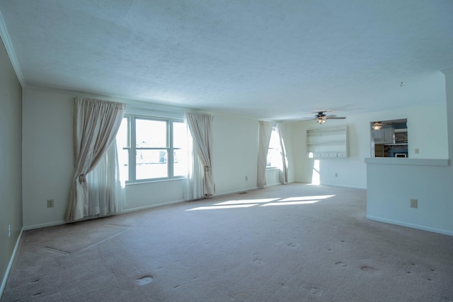 carpeted empty room with ceiling fan, ornamental molding, and a wealth of natural light