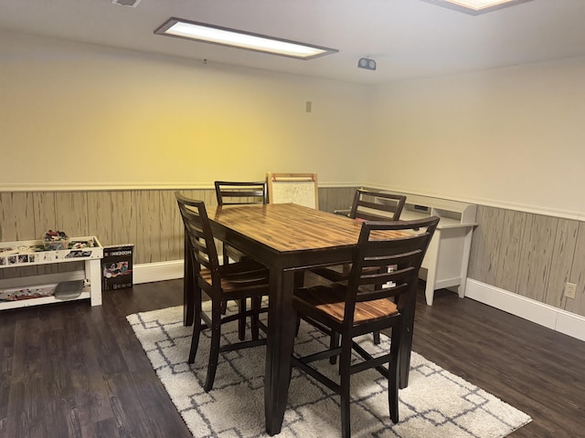 dining space with wooden walls and dark hardwood / wood-style flooring