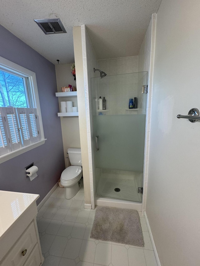 bathroom featuring vanity, toilet, a shower with shower door, and a textured ceiling