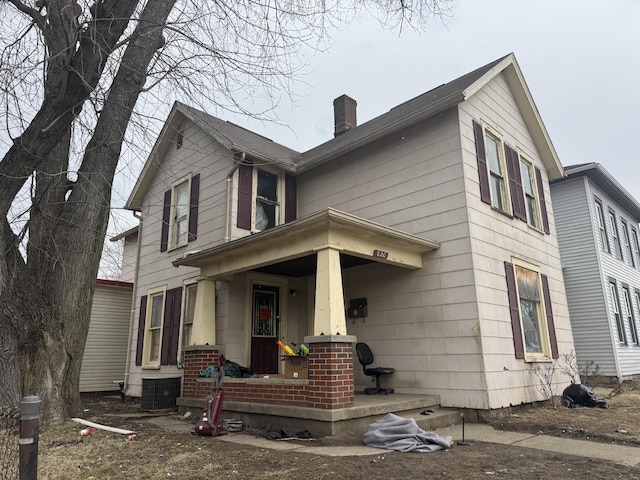 view of front of house featuring covered porch, central AC unit, and a chimney