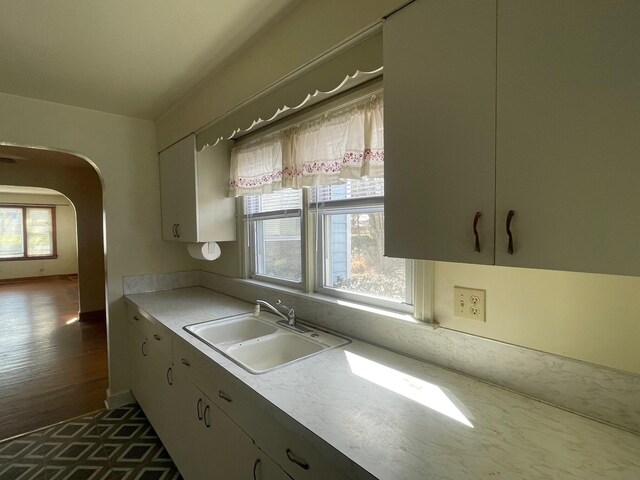 kitchen with light countertops, a healthy amount of sunlight, arched walkways, and a sink