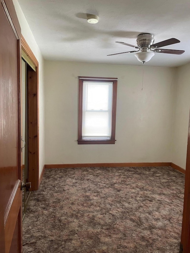 carpeted empty room featuring baseboards and ceiling fan