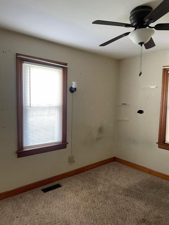unfurnished room with visible vents, baseboards, carpet, and a ceiling fan