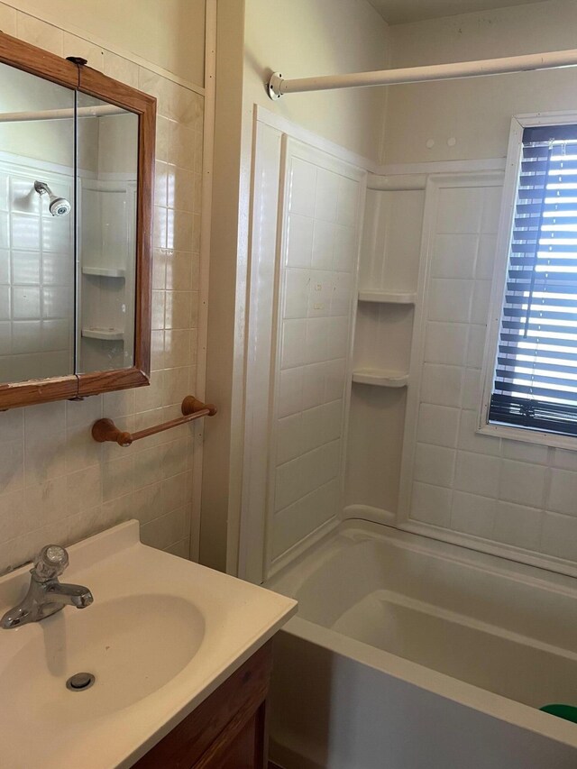 bathroom with backsplash, vanity, tile walls, and washtub / shower combination