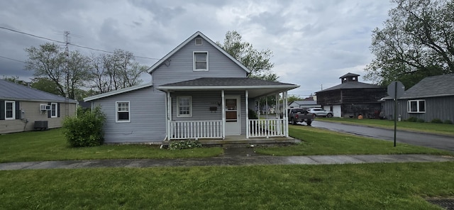 view of front of property featuring covered porch, cooling unit, and a front yard