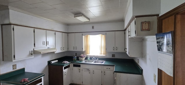 kitchen featuring a sink, under cabinet range hood, white cabinets, dark countertops, and crown molding