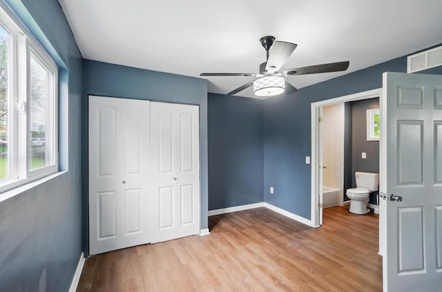 925 E St, Springfield, OH 45505 - unfurnished bedroom with a closet, multiple windows, baseboards, and light wood-style floors