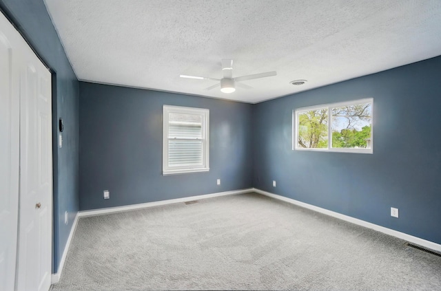 925 E St, Springfield, OH 45505 - unfurnished bedroom featuring a textured ceiling, carpet floors, multiple windows, baseboards, and a ceiling fan