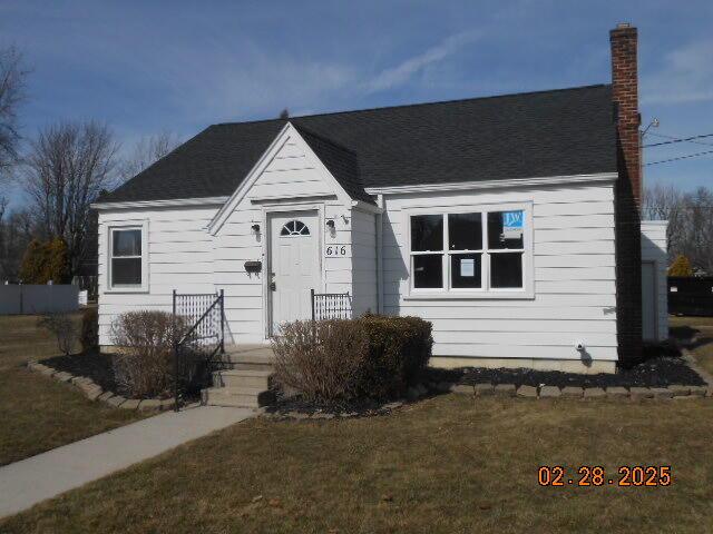 view of front facade with a front yard and a chimney