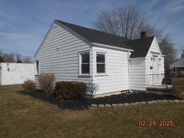 view of home's exterior featuring a chimney, fence, and a lawn