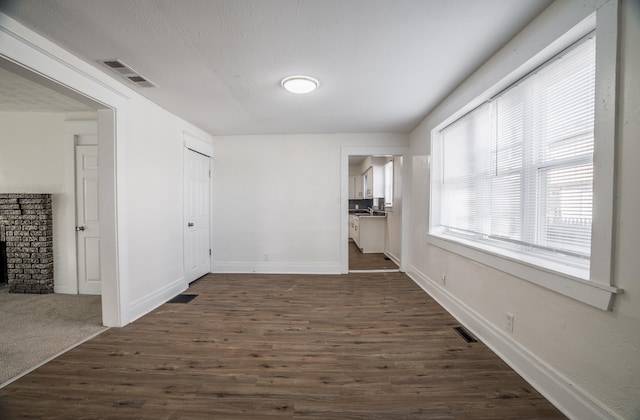 interior space with baseboards, visible vents, and dark wood-style floors