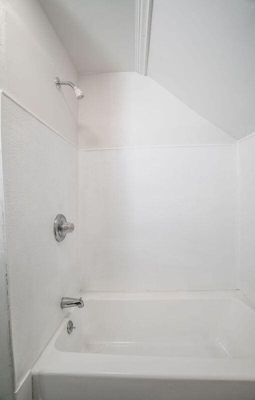 bathroom featuring lofted ceiling and bathtub / shower combination