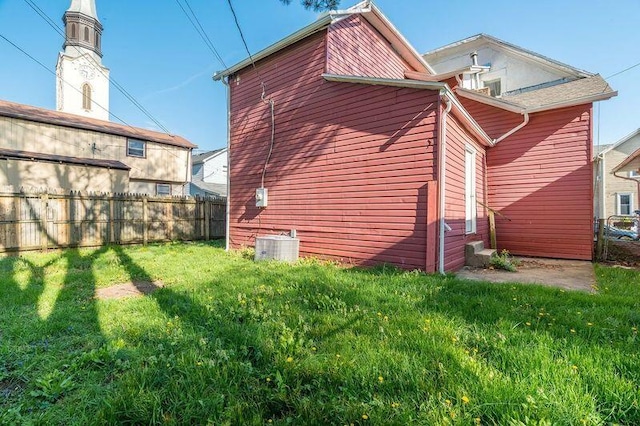 back of house with a yard, fence, and central air condition unit