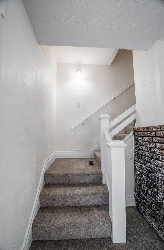 stairs with carpet flooring and a textured ceiling