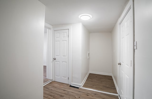 hallway featuring baseboards, wood finished floors, and visible vents
