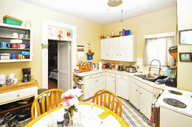 kitchen featuring light countertops, a sink, white electric range oven, and white cabinets