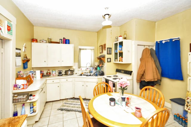 kitchen featuring light countertops, a sink, white cabinetry, and electric stove