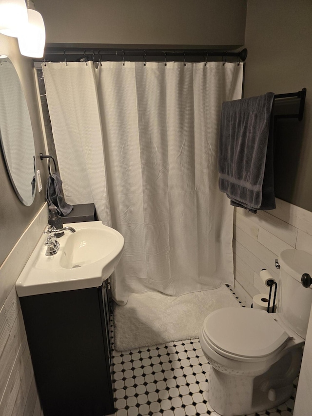 full bath with a shower with shower curtain, toilet, tile walls, and vanity