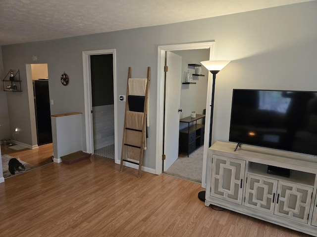 living area with wood finished floors, baseboards, and a textured ceiling