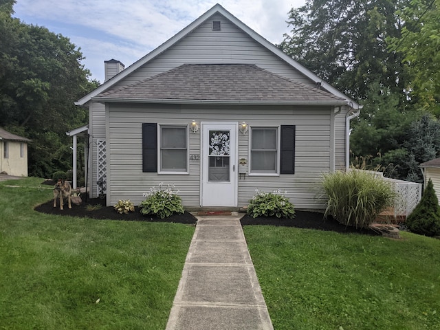 bungalow-style house with a front lawn, a chimney, and a shingled roof