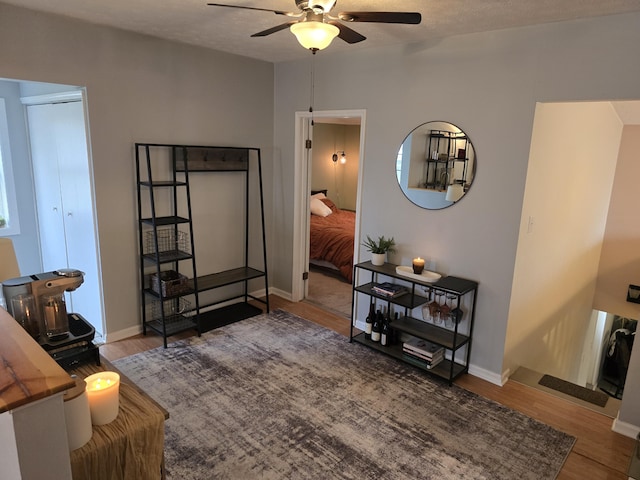 interior space with baseboards, wood finished floors, and ceiling fan