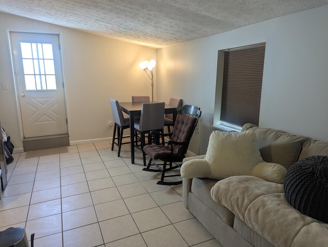 living area with light tile patterned flooring, baseboards, and a textured ceiling