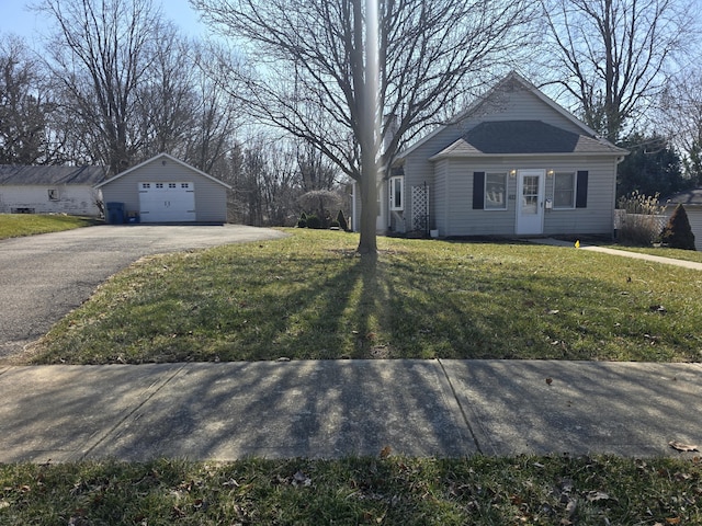 view of front of property with a front yard, an outbuilding, a garage, and aphalt driveway