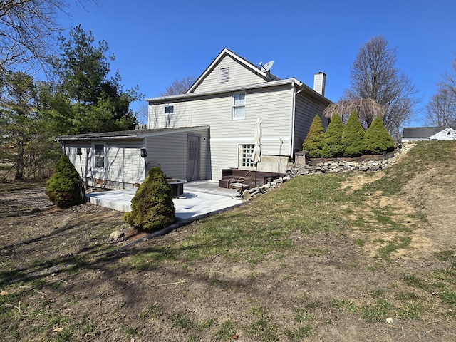 back of property with a yard, a patio area, and a chimney