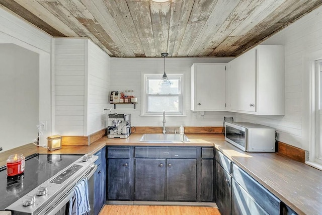 kitchen with a sink, light countertops, appliances with stainless steel finishes, white cabinetry, and wooden ceiling