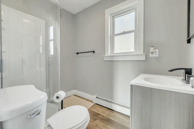 bathroom with a shower stall, a baseboard heating unit, toilet, wood finished floors, and vanity